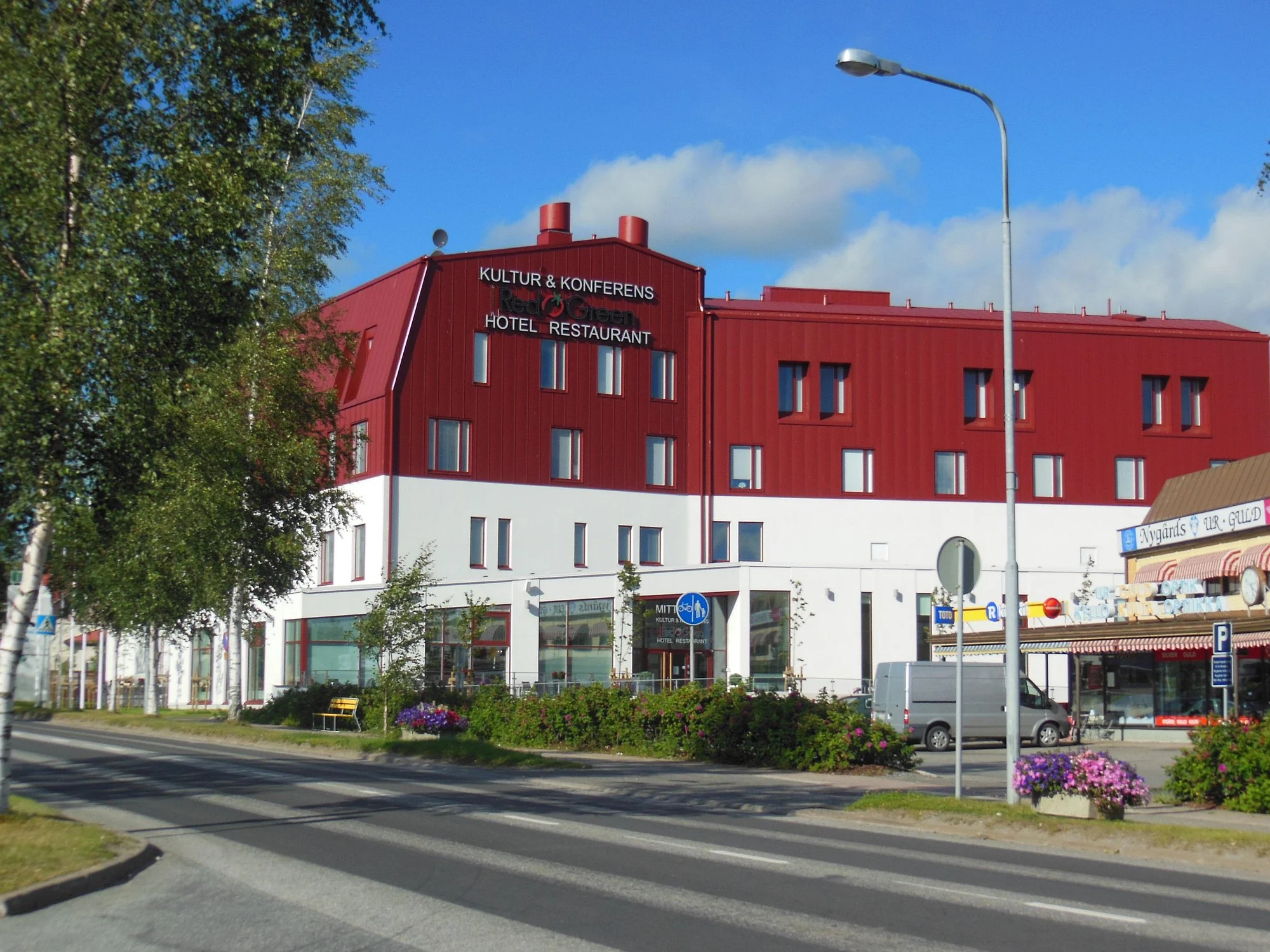 Hotel Red & Greens röda och vita fasad under en blå sommarhimmel.